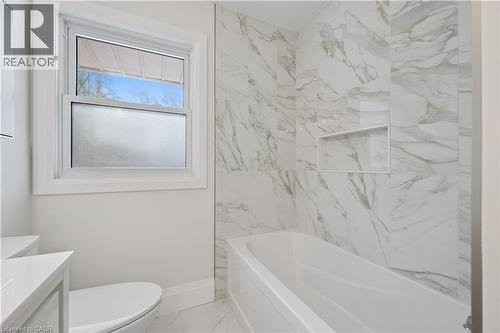 Full bathtub with an integrated soap niche, surrounded by large format tile with natural stone veining - 111 Ruskview Road, Kitchener, ON - Indoor Photo Showing Bathroom