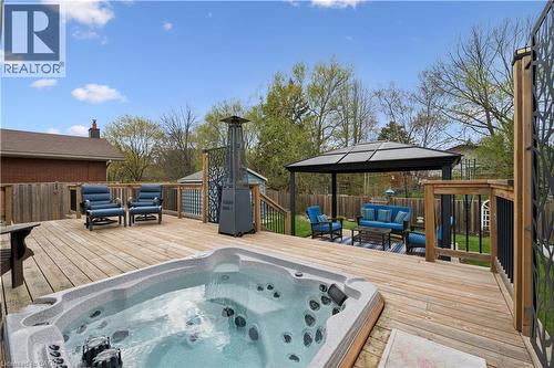 Expansive wood deck featuring a built-in hot tub, black metal gazebo, and decorative black metal balusters - 111 Ruskview Road, Kitchener, ON - Outdoor With Deck Patio Veranda