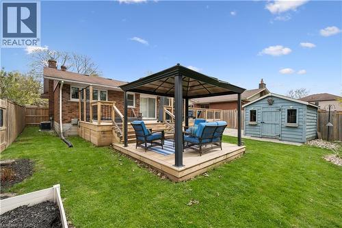 Expansive backyard featuring a large elevated wood deck with stairs, a ground-level wood patio with a gazebo, a detached storage shed, and mature fencing - 111 Ruskview Road, Kitchener, ON - Outdoor With Exterior