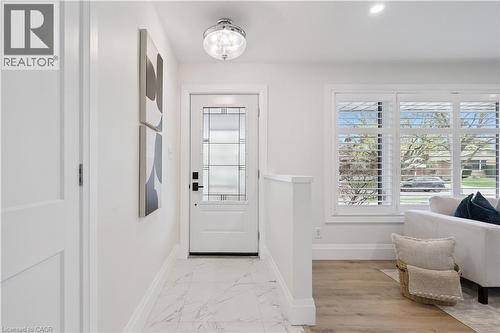 Entryway with a white paneled door featuring decorative glass inserts, polished chrome flush mount lighting, and marble-look tile flooring - 111 Ruskview Road, Kitchener, ON - Indoor Photo Showing Other Room