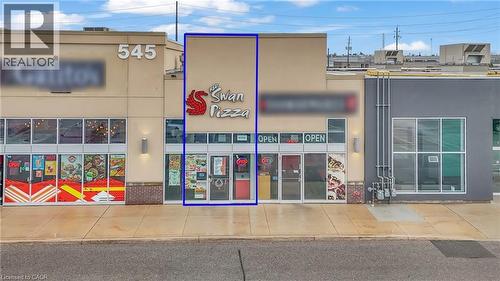 Commercial storefront with a large sign, full-height glass entry doors, and a light-colored facade - 545 Hespeler Road, Cambridge, ON 