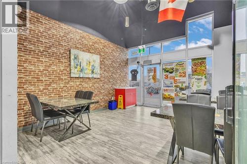 Interior space featuring an exposed brick wall, wood-finish flooring, and expansive storefront windows - 545 Hespeler Road, Cambridge, ON 