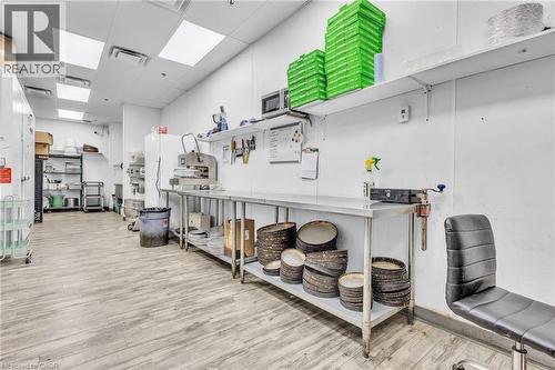 Commercial kitchen space featuring light wood-finish flooring, white panel walls, and multiple stainless steel prep tables - 545 Hespeler Road, Cambridge, ON 