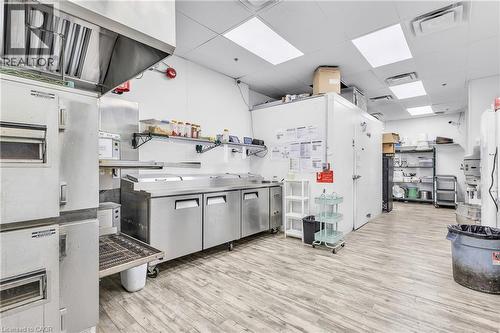 Commercial kitchen space featuring a stainless steel exhaust hood, built-in stainless steel refrigeration units, and extensive stainless steel countertops - 545 Hespeler Road, Cambridge, ON 
