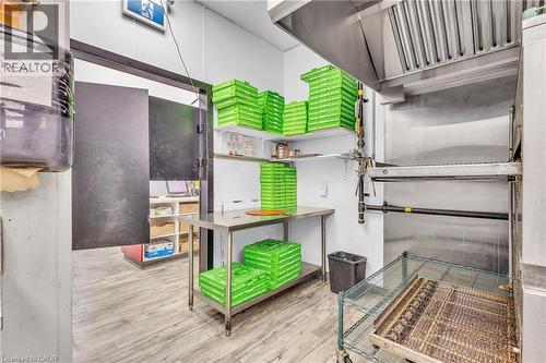 Commercial kitchen space featuring a stainless steel exhaust hood, stainless steel shelving, and wood-finish flooring - 545 Hespeler Road, Cambridge, ON 