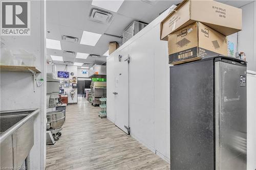 Spacious commercial kitchen area featuring light wood-finish flooring and a white drop ceiling with square lighting panels - 545 Hespeler Road, Cambridge, ON 