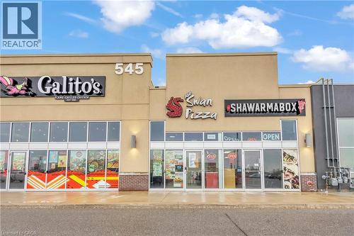Commercial storefronts featuring large glass windows, beige stucco facade, brick accents, and modern exterior lighting - 545 Hespeler Road, Cambridge, ON 
