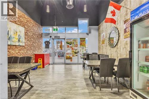 Commercial interior featuring a brick accent wall, wood-finish flooring, and a dark ceiling with exposed ductwork - 545 Hespeler Road, Cambridge, ON 