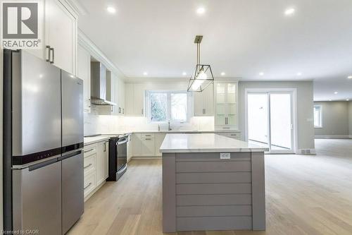 Dual tone kitchen featuring stainless steel appliances, backsplash, a center island, light wood-style flooring, and two tone cabinetry - 1105 Main Street E, Cambridge, ON - Indoor Photo Showing Kitchen With Stainless Steel Kitchen With Upgraded Kitchen
