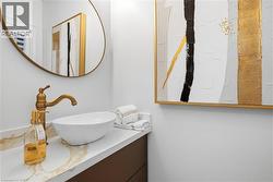 Vessel sink with a brass-finish faucet set on a white countertop with gold-veined detailing - 