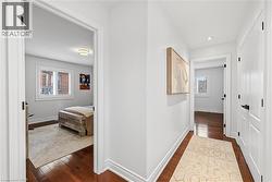Hallway featuring rich wood-finish flooring, white trim, and recessed lighting - 