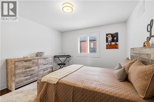 Bedroom featuring a window with white louvered shutters, a wood-finish bed frame, and a complementary wood-finish dresser with dark hardware - 199 Hunter Street W, Hamilton, ON - Indoor Photo Showing Bedroom