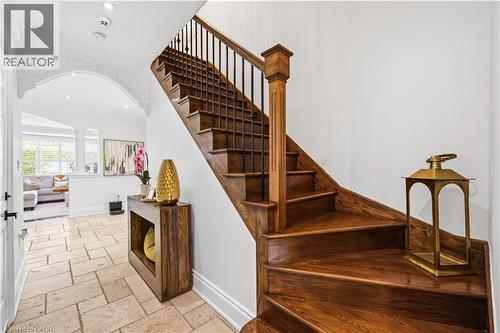 Rich wood staircase with black iron balusters, featuring a substantial newel post - 199 Hunter Street W, Hamilton, ON - Indoor Photo Showing Other Room