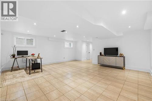 Spacious room featuring light-toned square floor tiling, multiple recessed ceiling lights, and white baseboards - 199 Hunter Street W, Hamilton, ON - Indoor