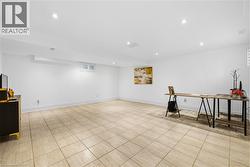 Spacious interior room featuring light-toned square floor tiles and white painted walls - 