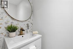 White vanity with integrated sink, brass waterfall faucet, and round brass-framed mirror - 