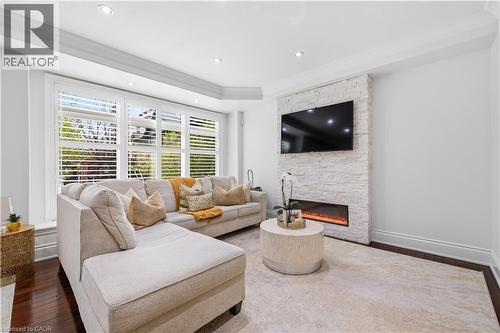Living area featuring a stone accent wall with an inset electric fireplace, recessed lighting, and crown molding - 199 Hunter Street W, Hamilton, ON - Indoor Photo Showing Living Room With Fireplace