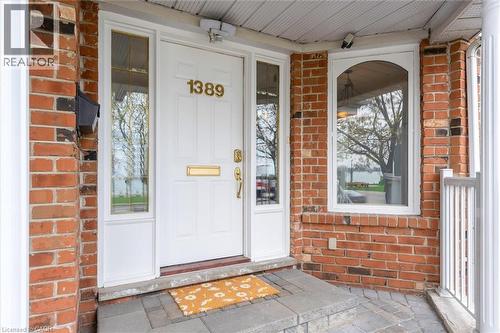 Brick exterior featuring a white paneled entry door with sidelights, an arched window, and a white porch railing - 1389 Lakeshore Road, Burlington, ON - Outdoor With Exterior