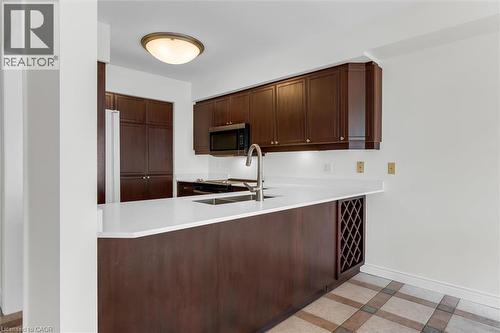 Kitchen featuring dark wood cabinetry, light countertops, built-in wine rack, and tile flooring - 1389 Lakeshore Road, Burlington, ON - Indoor Photo Showing Kitchen With Double Sink