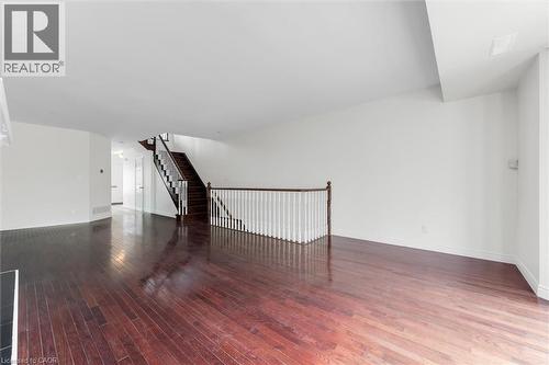 Spacious room featuring rich wood-finish flooring, white walls, and a contrasting dark wood staircase with white balusters - 1389 Lakeshore Road, Burlington, ON - Indoor Photo Showing Other Room