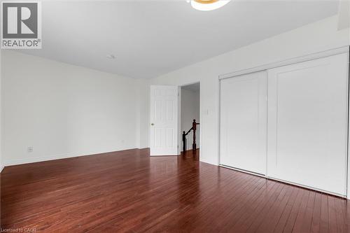 Spacious room featuring rich wood-finish flooring, white walls, and a contemporary ceiling light fixture - 1389 Lakeshore Road, Burlington, ON - Indoor Photo Showing Other Room