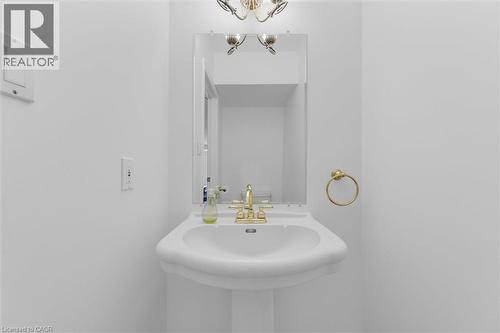 Pedestal sink with brass-finish faucet, framed mirror, and brass-finish towel ring - 1389 Lakeshore Road, Burlington, ON - Indoor Photo Showing Bathroom