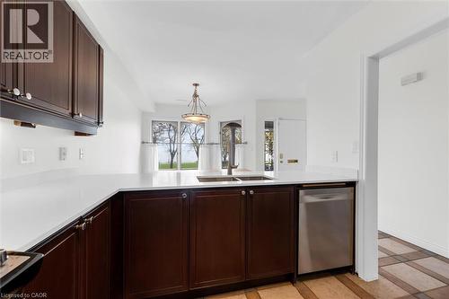 Kitchen featuring dark wood cabinetry, white countertops, stainless steel sink with a gooseneck faucet, and a stainless steel dishwasher - 1389 Lakeshore Road, Burlington, ON - Indoor Photo Showing Kitchen