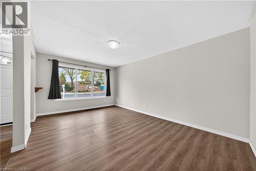 Spacious room featuring wood-finish flooring, light neutral wall paint, and a large multi-pane window - 34 Avenue Road, Cambridge, ON - Indoor