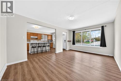 Open-concept living area featuring wood-finish flooring, a large picture window, and a pass-through to the kitchen with a breakfast bar - 34 Avenue Road, Cambridge, ON - Indoor Photo Showing Living Room