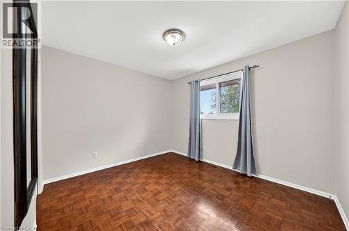 Room featuring wood-finish parquet flooring, neutral wall tones, a single window, and a flush-mount ceiling light fixture - 34 Avenue Road, Cambridge, ON - Indoor Photo Showing Other Room