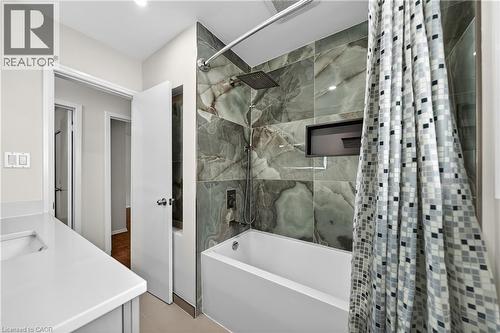 Bathroom featuring a white soaking tub with a rain shower head, large-format grey-veined wall tile, and a recessed shower niche - 34 Avenue Road, Cambridge, ON - Indoor Photo Showing Bathroom