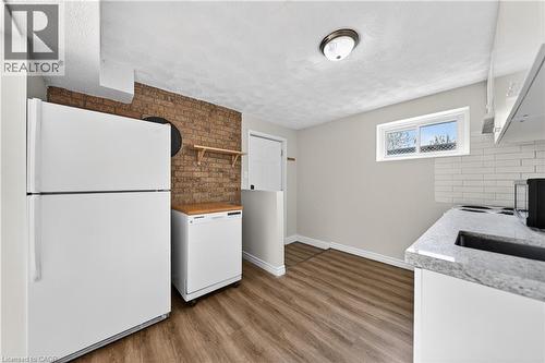 Kitchen featuring wood-finish flooring, a white subway tile backsplash, and a light gray countertop with an integrated sink - 34 Avenue Road, Cambridge, ON - Indoor Photo Showing Kitchen