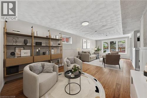 Spacious living area featuring wood-finish flooring, a full wall of built-in shelving with integrated lighting, and a large window providing ample natural light - 34 Avenue Road, Cambridge, ON - Indoor