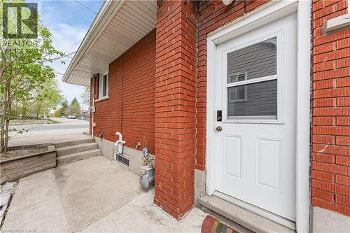 Brick exterior featuring a white entry door with an integrated screen, a concrete pathway, and steps - 34 Avenue Road, Cambridge, ON - Outdoor With Exterior
