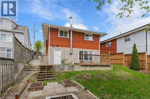 Rear exterior featuring a red brick facade, wood deck with railing, and a sloped lawn area - 34 Avenue Road, Cambridge, ON - Outdoor With Deck Patio Veranda