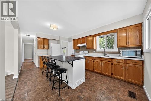 Kitchen featuring wood cabinetry, white countertops, tile flooring, and a central island - 34 Avenue Road, Cambridge, ON - Indoor Photo Showing Kitchen