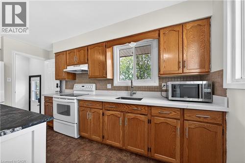 Kitchen featuring wood cabinetry with silver hardware, light-toned countertops, and a white electric range with an overhead exhaust fan - 34 Avenue Road, Cambridge, ON - Indoor Photo Showing Kitchen