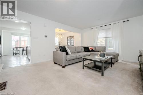Carpeted living area featuring an open archway, a large window with blinds and drapes, and recessed lighting - 525 Cavanagh Lane, Milton, ON - Indoor Photo Showing Living Room