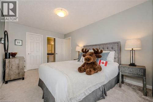 Bedroom featuring light gray walls, plush carpeting, a tufted fabric headboard, and a ceiling-mounted light fixture - 525 Cavanagh Lane, Milton, ON - Indoor Photo Showing Bedroom