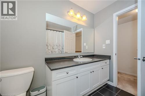 Bathroom featuring a white vanity with shaker-style cabinetry, dark countertop, and an undermount sink - 525 Cavanagh Lane, Milton, ON - Indoor Photo Showing Bathroom