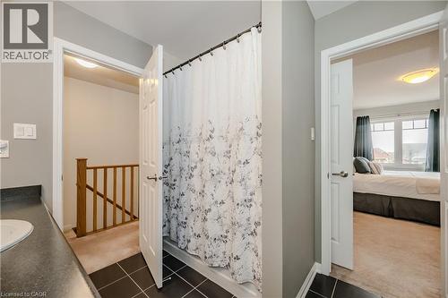 Bathroom featuring dark tile flooring, a white shower curtain, and a vanity with a dark countertop - 525 Cavanagh Lane, Milton, ON - Indoor Photo Showing Bathroom