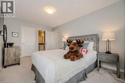 Bedroom featuring light gray walls, plush carpeting, a tufted fabric headboard, and a ceiling-mounted light fixture - 