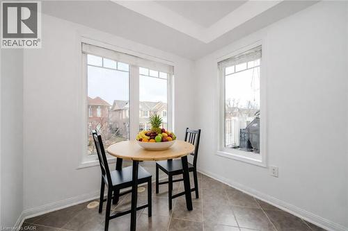 Bright dining area featuring a large window with white trim, tray ceiling, and neutral tiled flooring - 525 Cavanagh Lane, Milton, ON - Indoor Photo Showing Dining Room