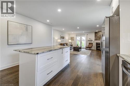 Kitchen island featuring white cabinetry, integrated storage, and a light-toned stone countertop - 29 Wiltshire Place, Ancaster, ON - Indoor Photo Showing Kitchen