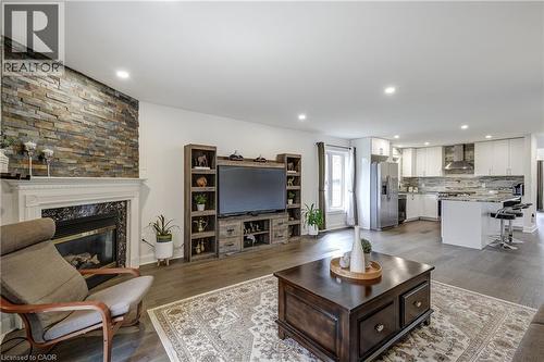 Spacious living area featuring a stone accent wall, fireplace with white mantel, and wood-finish flooring - 29 Wiltshire Place, Ancaster, ON - Indoor Photo Showing Living Room With Fireplace