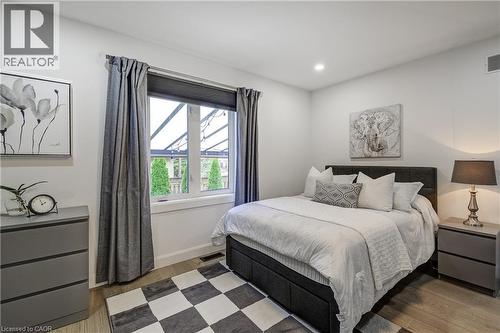 Bedroom featuring a large window with roller shades and full-length curtains, recessed lighting, and wood-finish flooring - 29 Wiltshire Place, Ancaster, ON - Indoor Photo Showing Bedroom