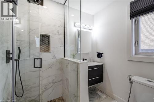 Glass-enclosed shower with large format marble-look tile, matte black fixtures, and a hexagonal tile shower niche - 29 Wiltshire Place, Ancaster, ON - Indoor Photo Showing Bathroom