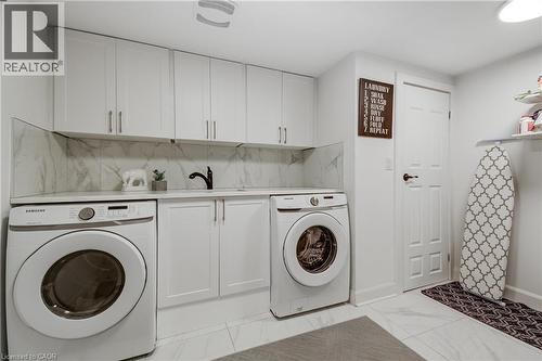 Dedicated laundry area featuring white shaker-style cabinetry, a white countertop, and a white tile backsplash - 29 Wiltshire Place, Ancaster, ON - Indoor Photo Showing Laundry Room