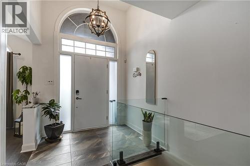 Grand entryway featuring a soaring ceiling, an arched transom window, a decorative chandelier, a glass railing, and large format floor tiles - 29 Wiltshire Place, Ancaster, ON - Indoor Photo Showing Other Room