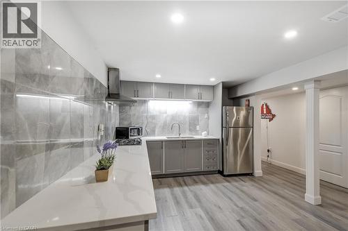 Modern kitchen featuring gray cabinetry, stainless steel appliances, light-toned countertops, a full-height tiled backsplash, and recessed lighting - 29 Wiltshire Place, Ancaster, ON - Indoor